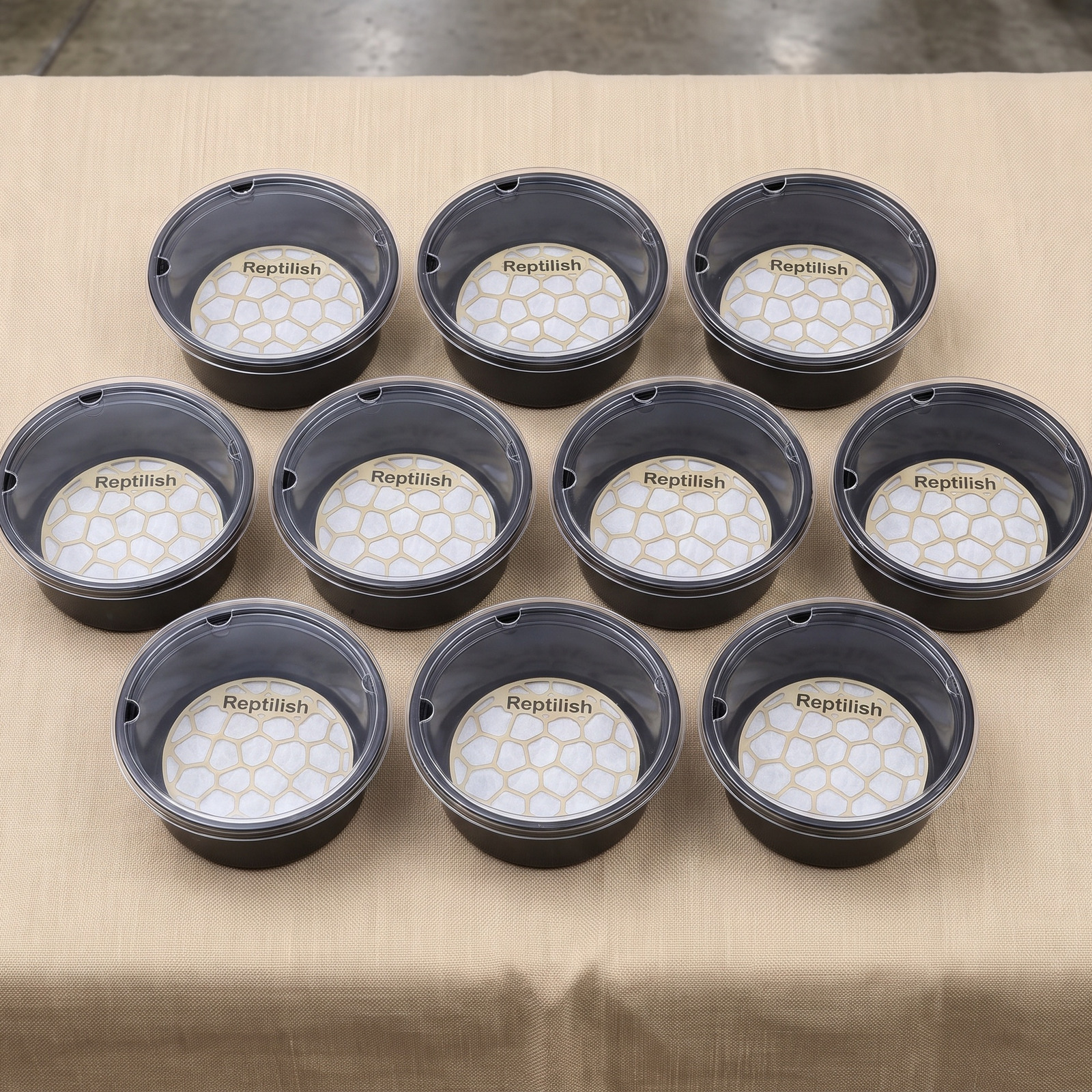 Contenitori tondi con coperchio in acrilico allineati su un tavolo espositivo in fiera