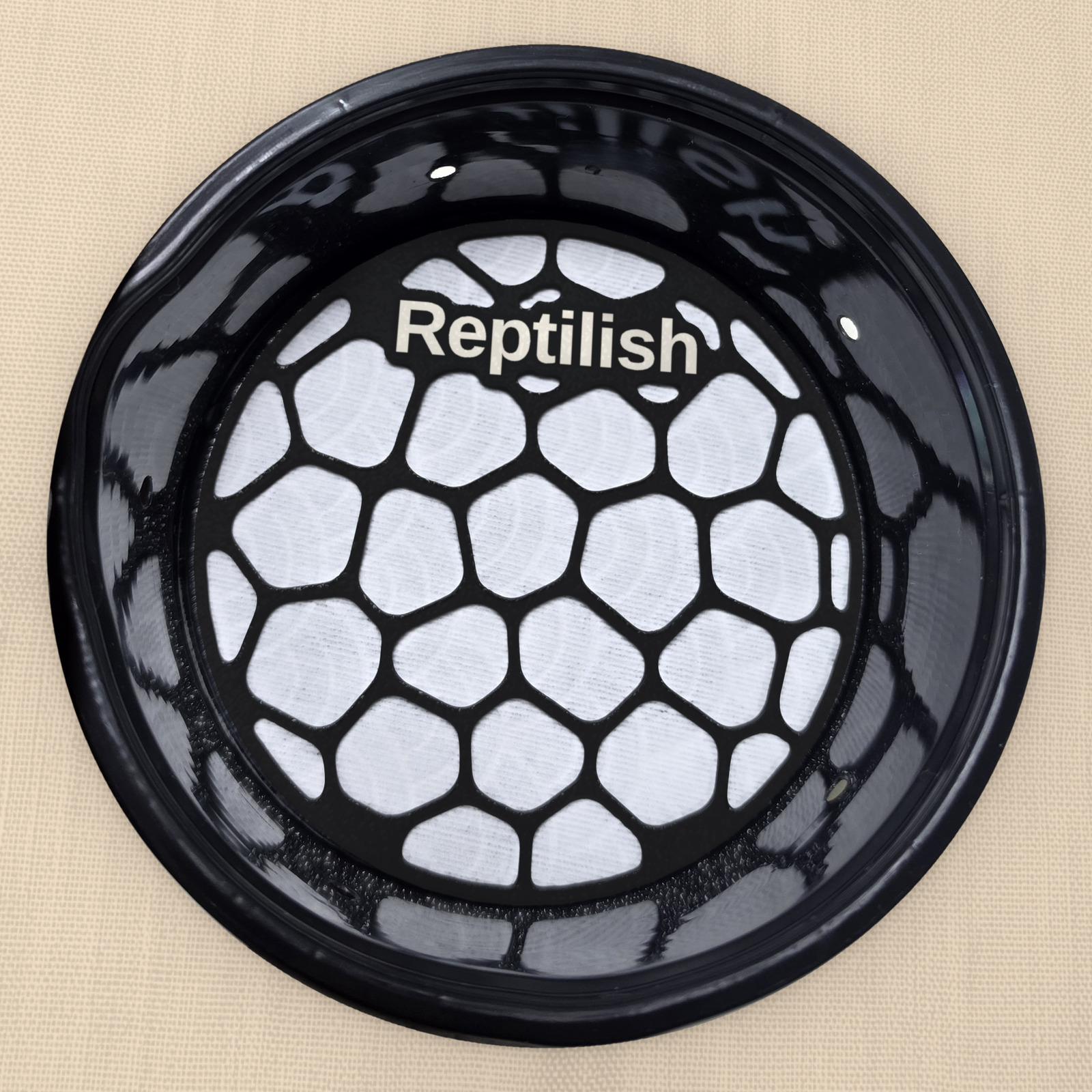 Piastra Pebble Plate tonda in Nero carbone con testo personalizzato, sul tappetino in un contenitore tondo (deli cup)